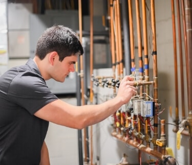 Technician Looking At Pipes In Basement